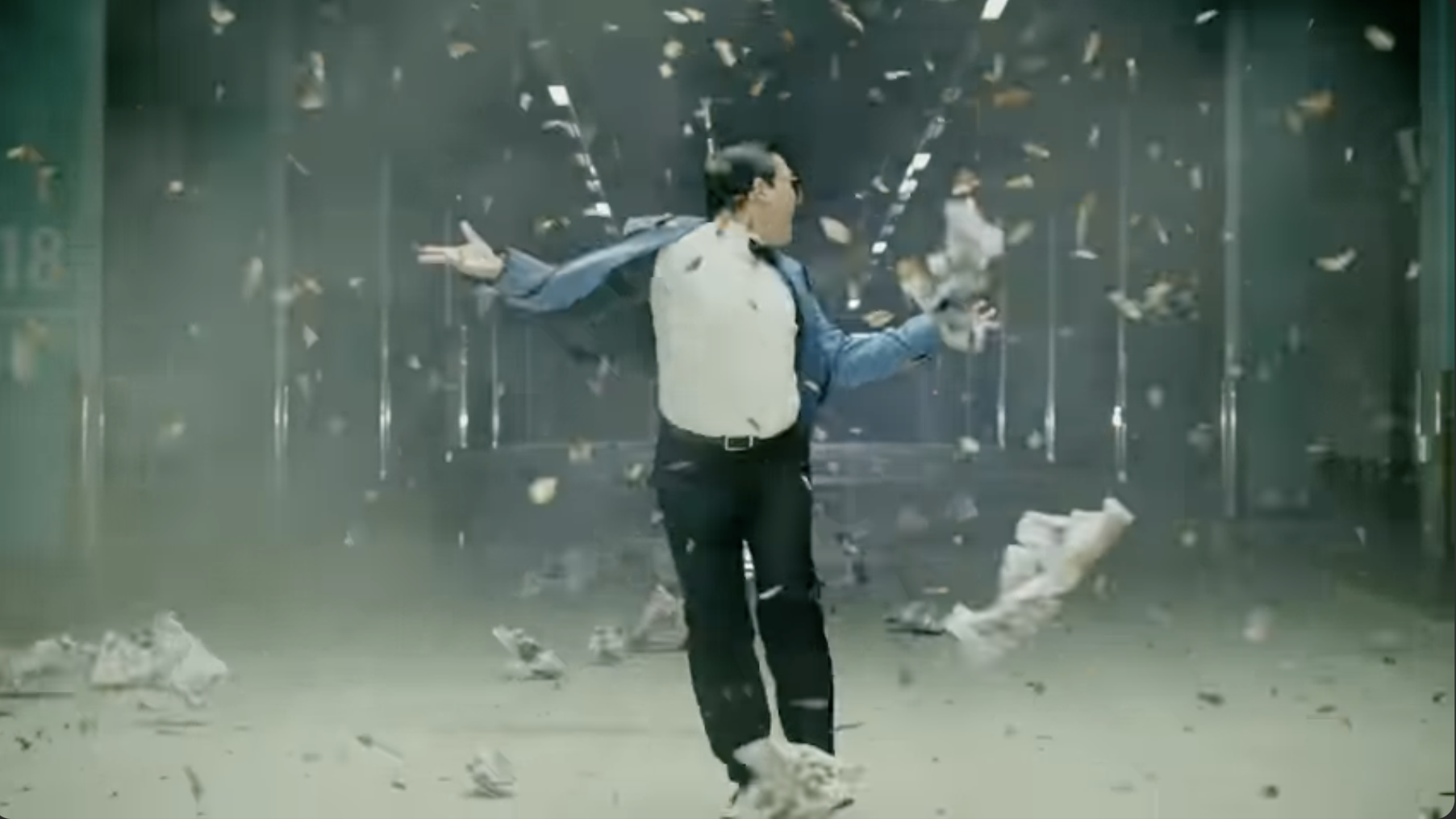 PSY walking through debris being blown his way